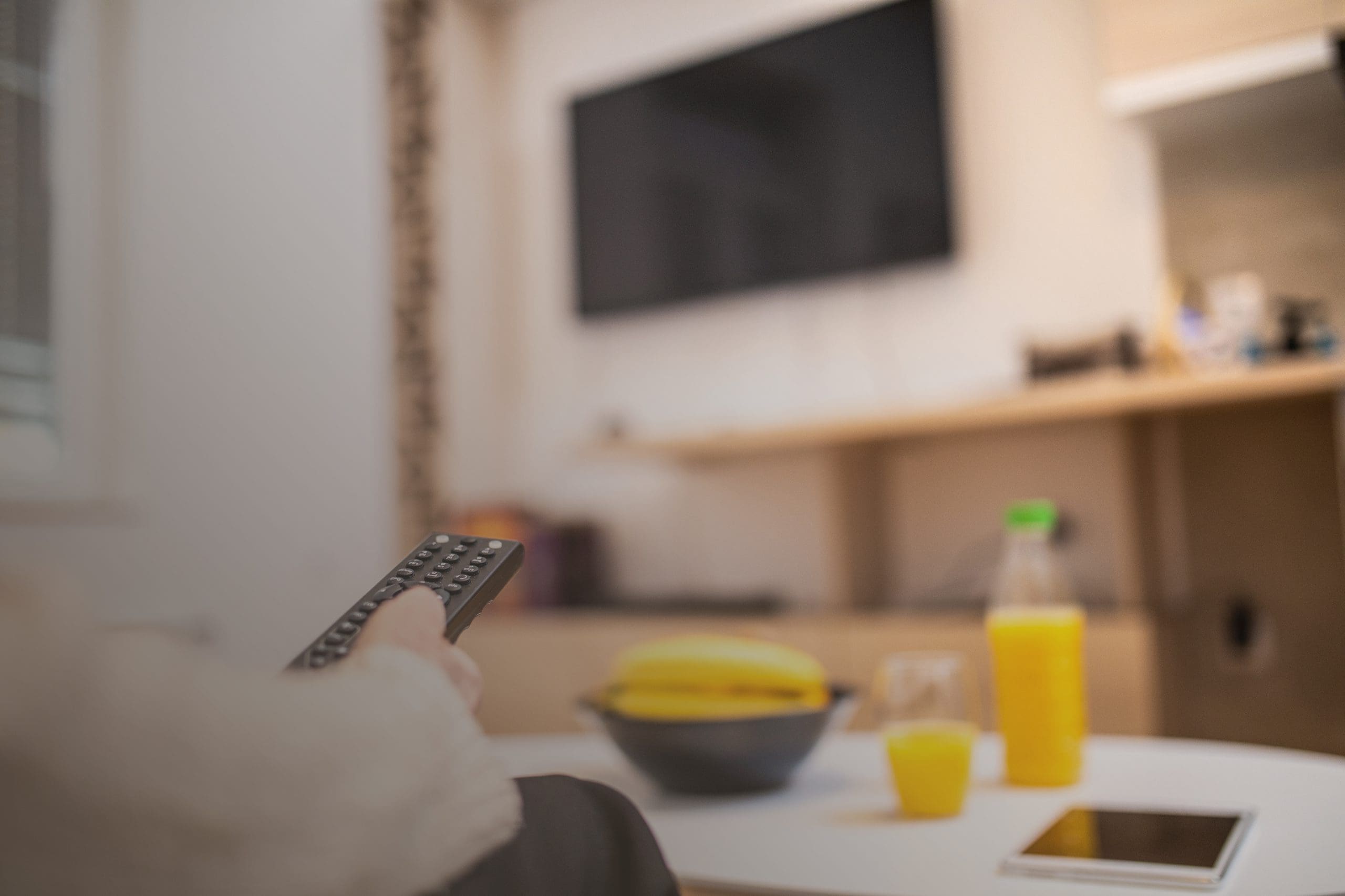 Close up of human hand holding remote control, changing channels in living room