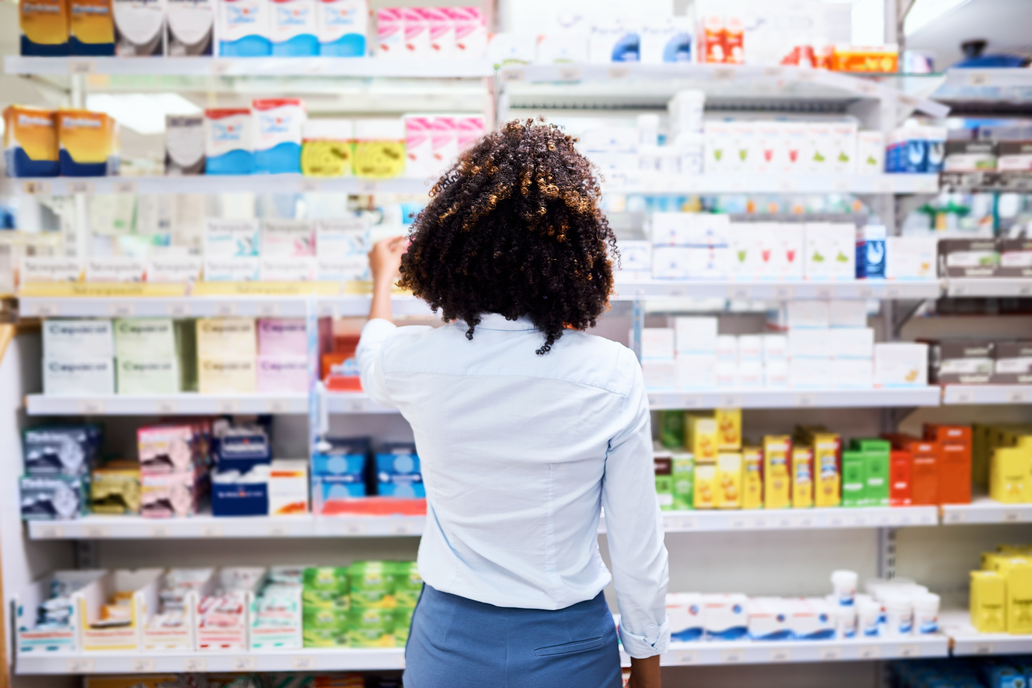 Rearview shot of a young woman looking at products in a pharmacy